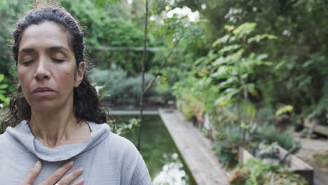 Focused-biracial-woman-practicing-yoga-in-sunny-garden-with-copy-space,-slow-motion