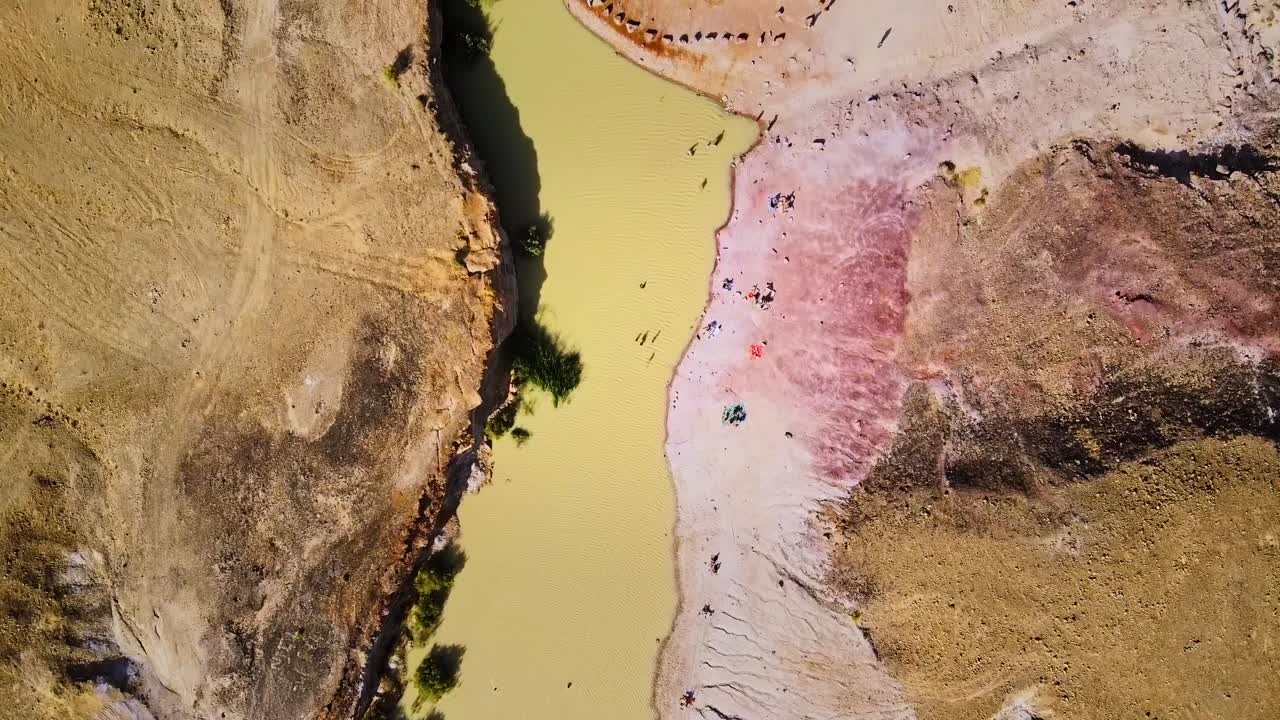 Top down aerial view of a pinkish salt lake in the dessert of Israel, with unique natural formations.