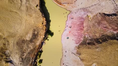 top down aerial view of a pinkish salt lake in the dessert of israel, with unique natural formations.