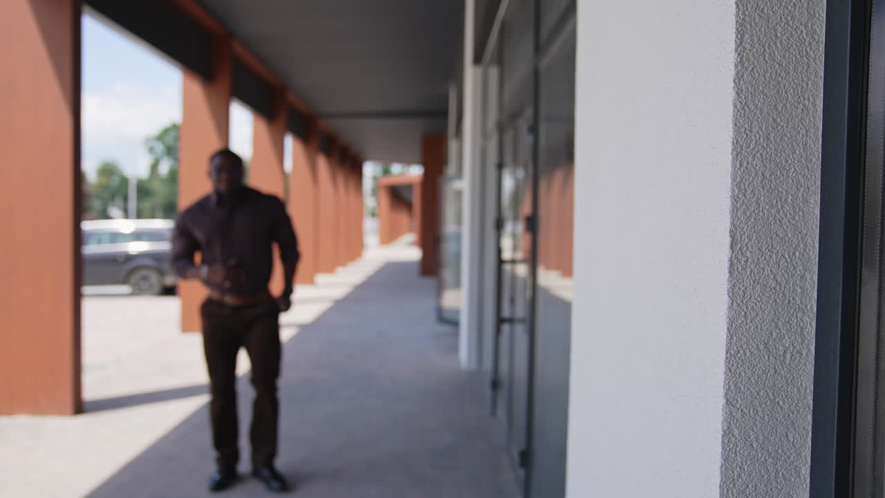 Black man standing in city street. Black man in suit walking on the street in the background