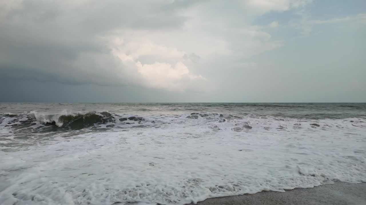 모래 해변에 부히는 물결의 느린 움직임, 구름이 가득한 여름 날