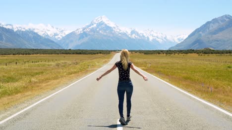 Rear-view-of-a-tourist-girl-enjoying-famous-State-Highway-80-next-to-lake-Pukaki-overlooking-Mt