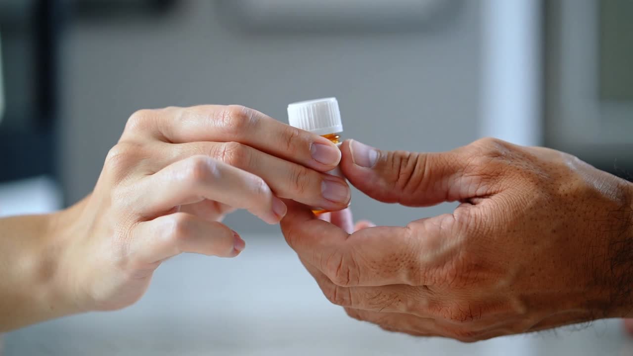 Lighter hand holding amber bottle white cap label, tanned hand reaching on table for meds