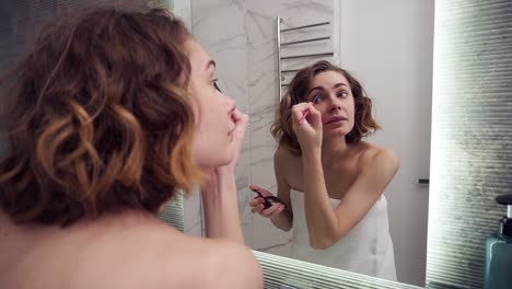 beautiful woman using eyebrow pencil make up in front mirror. happy female using beauty cosmetics to improve herself ready to working in bathroom at home. lifestyle women relax at home