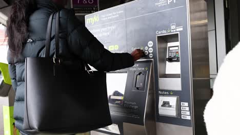 person topping up myki card at machine