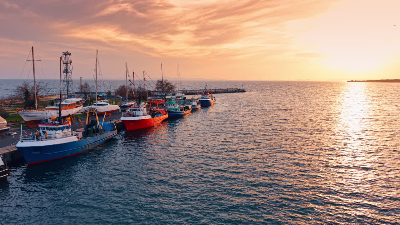 Volo lungo la banchina con grandi pescherecci. Splendido paesaggio marino colorato dalla luce soffusa del tramonto.