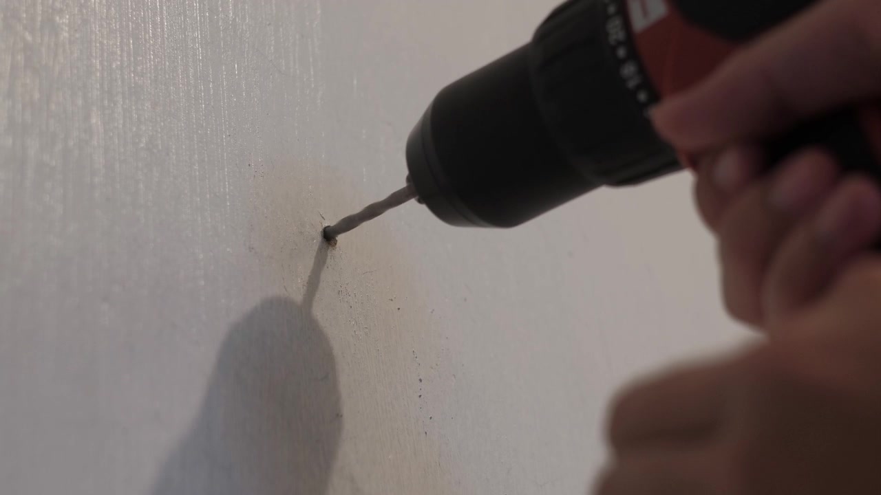 Close-up static shot of drilling into concrete wall during DIY installation using power drill for home improvement and interior setup