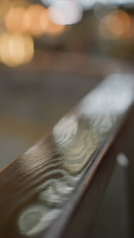 a close-up view of a polished handrail with a very blurry skiing area in the background.atmosphere of the skiing area in the background