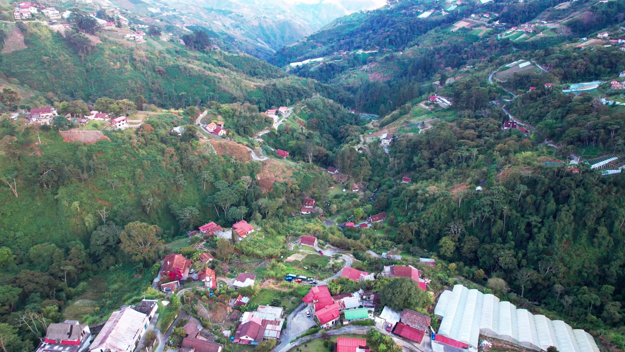 Drone shot rising to reveal a stunning alpine-style village surrounded by vast green mountains and mist in Venezuela