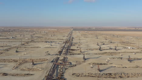 drone flight over working pump jacks on central california oil field
