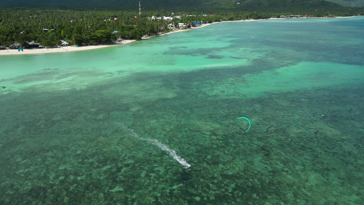 vista aérea de un kitesurfista acelerando en el agua clara del océano con la hermosa isla de koh phangan en el fondo
