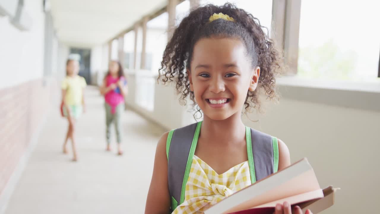 Video of happy biracial girl standing on school corridor