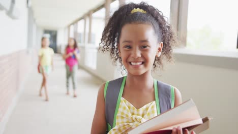 Video-of-happy-biracial-girl-standing-on-school-corridor