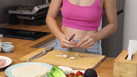 woman preparing a meal, chopping garlic and vegetables