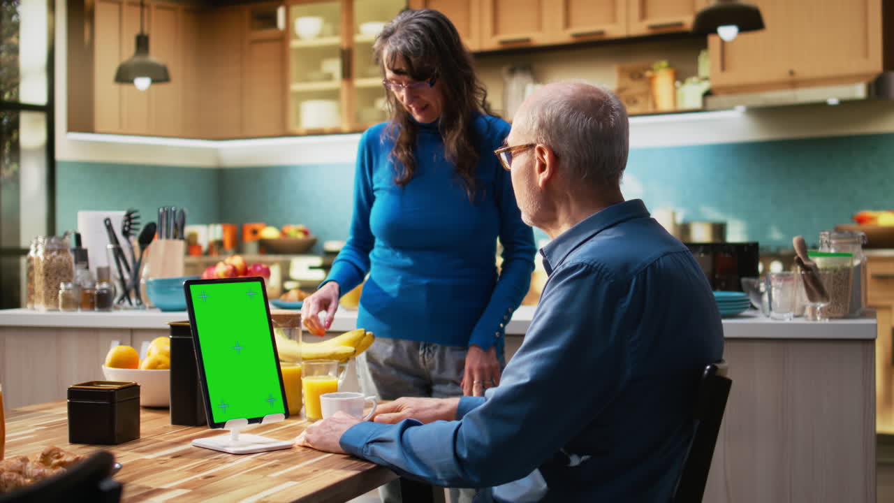 Vertical green screen with mature husband sitting at the kitchen table