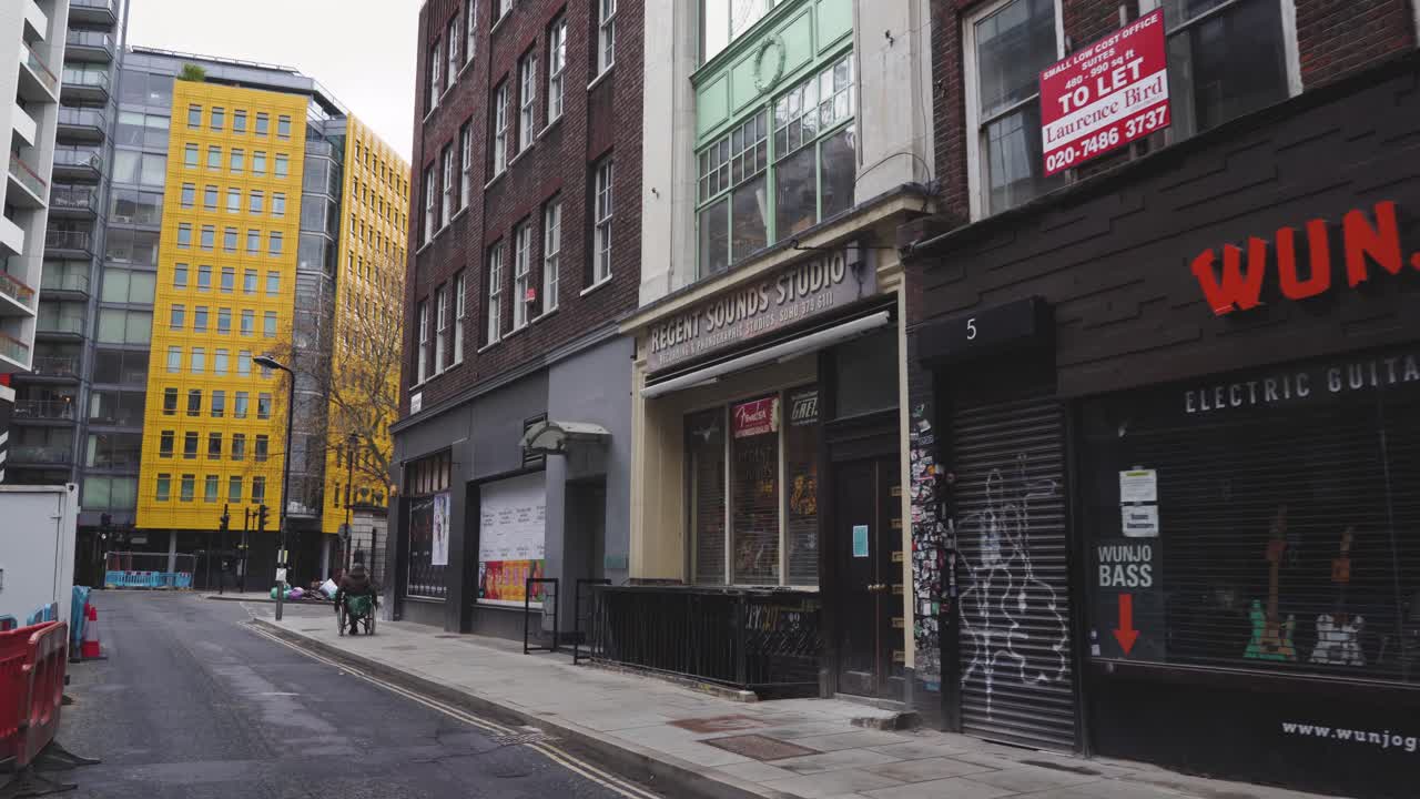 London - Empty Streets - Denmark Street with Central Saint Giles Plaza and a man in a wheelchair (Covid-19 Pandemic, April 10, 2021)