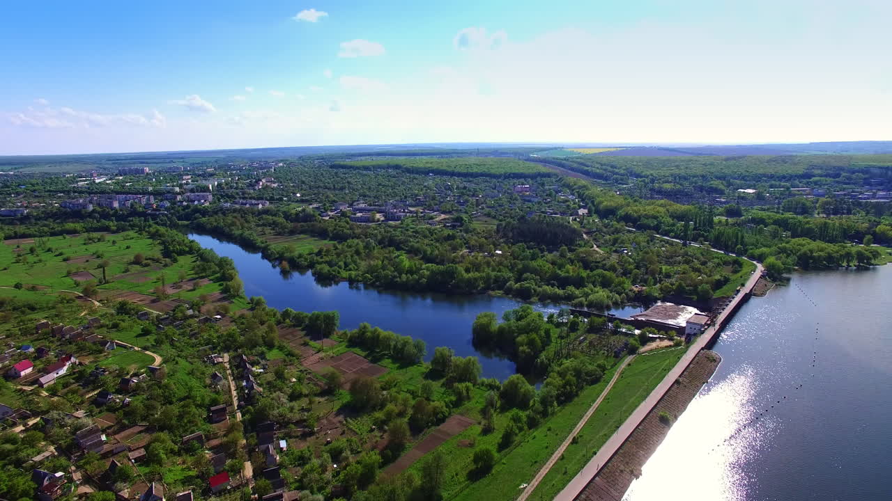 Amazing green urban landscape divided by river. Beautiful city panorama with water artery and dam on it. Aerial view.