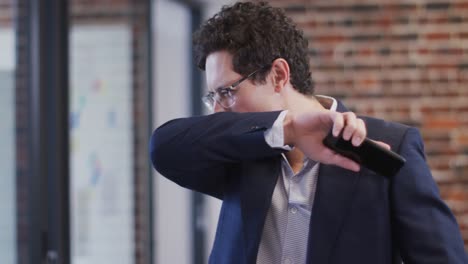 man sneezing on his elbow at office