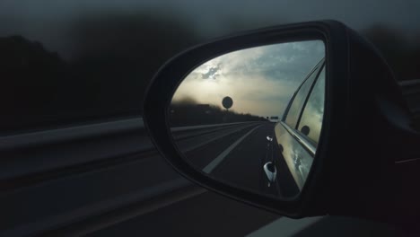 mirror of car in motion on road, cloudy day