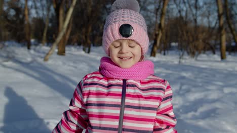 Cheerful-child-girl-kid-looking-at-camera,-making-faces,-fooling-around,-smiling-in-winter-park