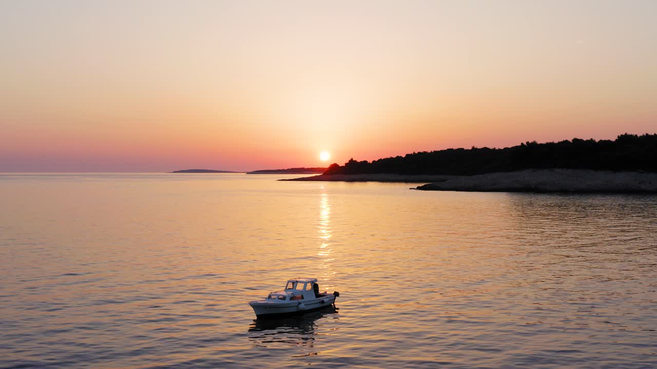 toma aérea de rango medio dando vueltas alrededor de un barco al atardecer frente a la costa de losinj, croacia