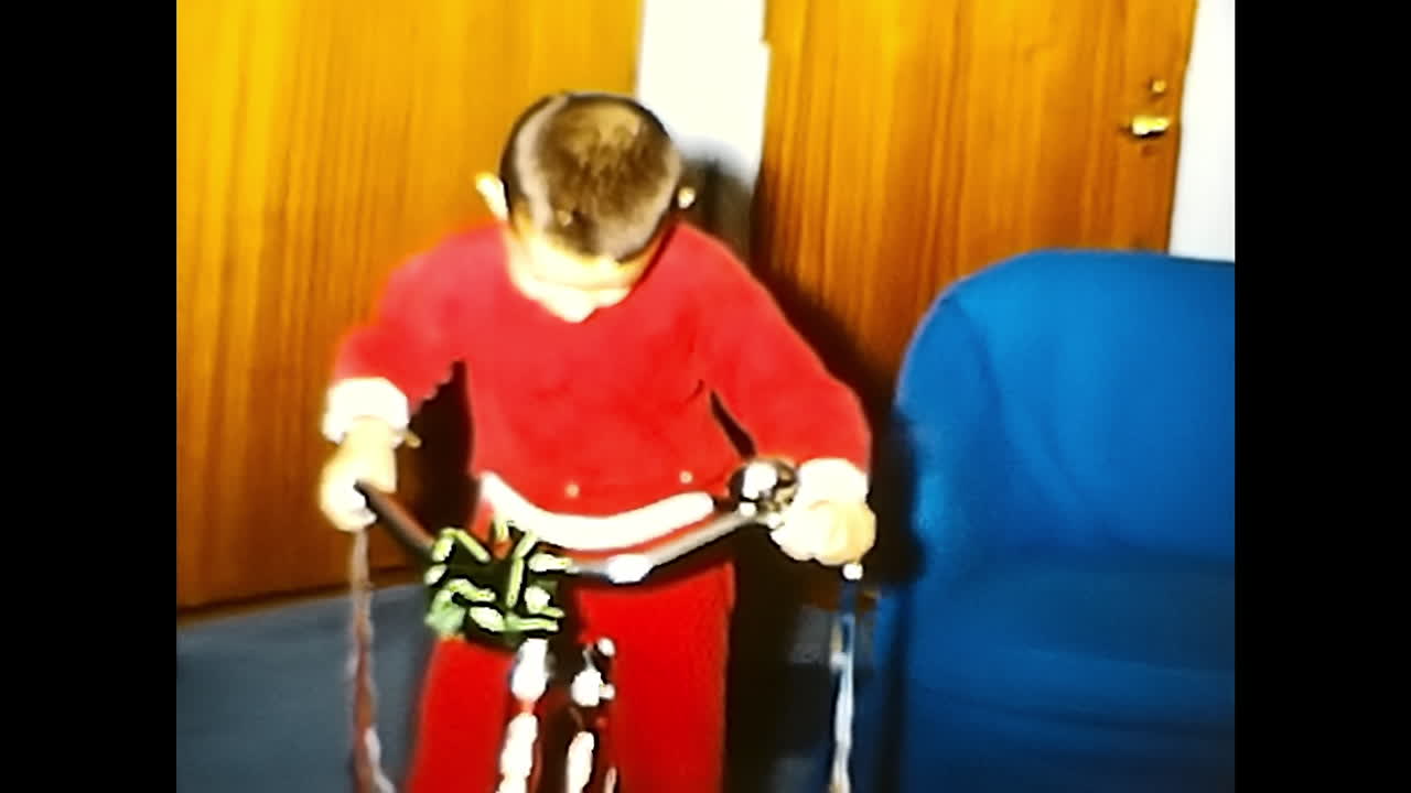 Person Riding Bike in Room. CIRCA USA - 1970s: A person is seen riding a bike in a 1970s room in the USA.