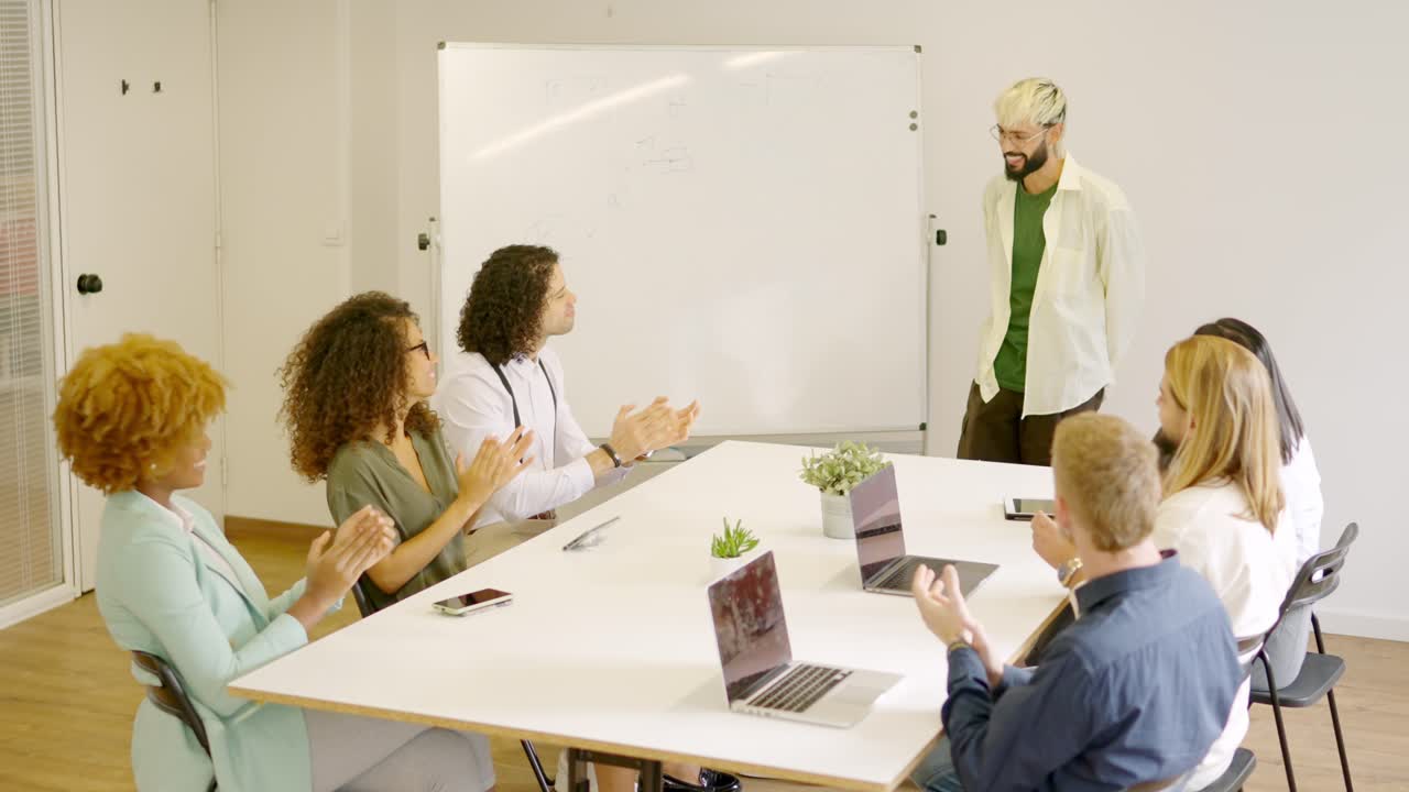 Coworkers applauding a man after a presentation using white board