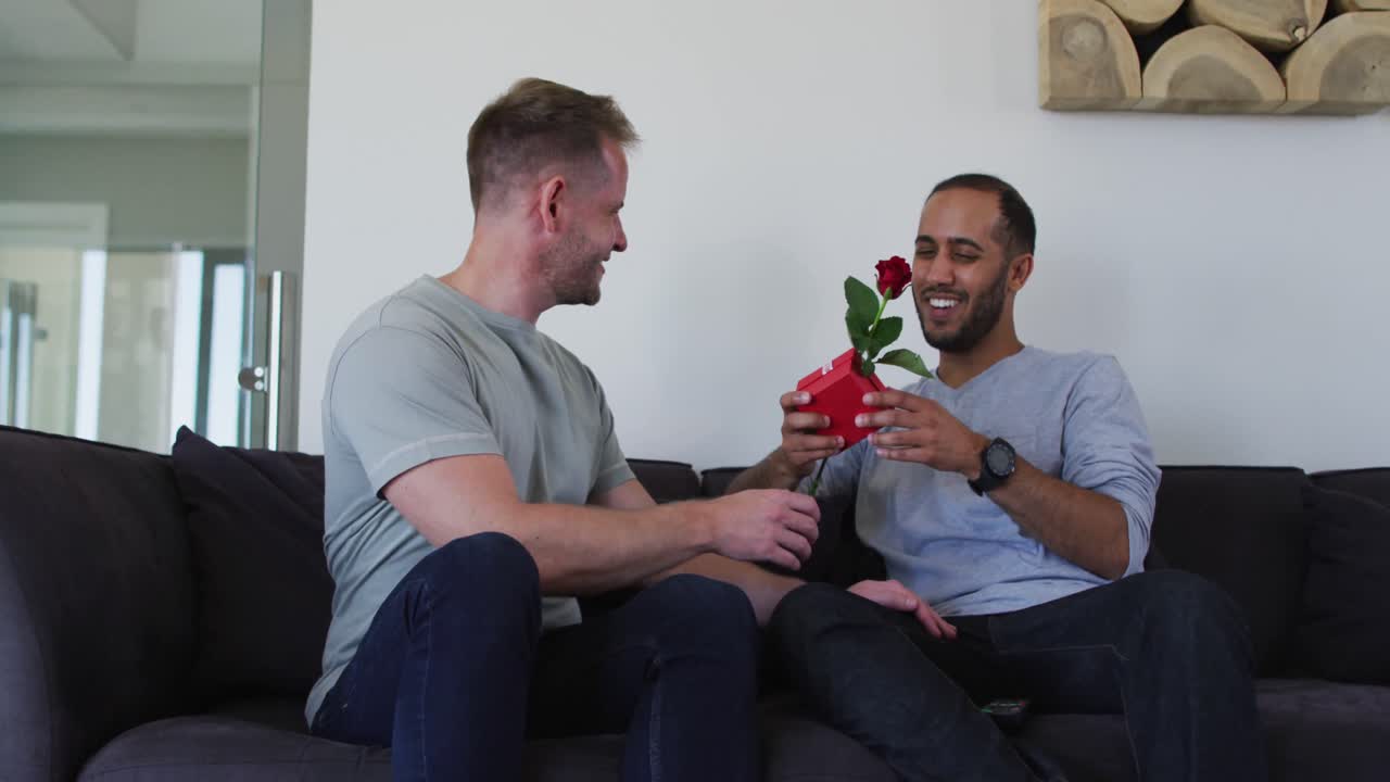 다민족 동성애자 남성 커플이 선물을 들고  ⁇ 안고 있습니다.