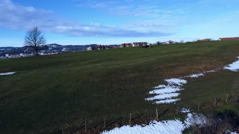 Revealing-the-city-behind-the-green,-snowy-hills-on-a-clear-day