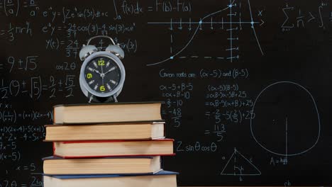 reloj despertador en la parte superior de una pila de libros y ecuaciones matemáticas y gráficos