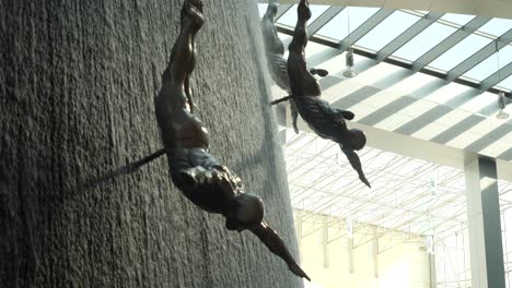 sculptures of swimmers in a waterfall wall