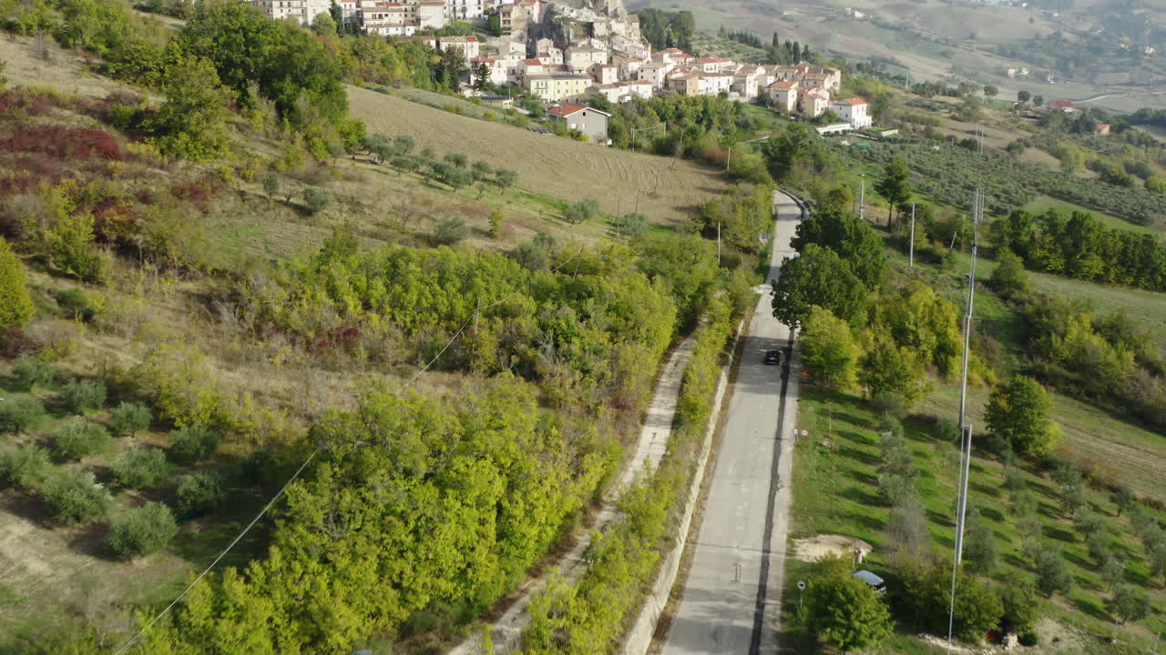 toma de revelación aérea de la ciudad de pietracupa en la región de molise en italia, siguiendo a un automóvil alquilado negro que conduce hacia la ciudad