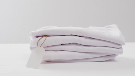 video de una pila de camisetas blancas plegadas con espacio de copia en un fondo blanco