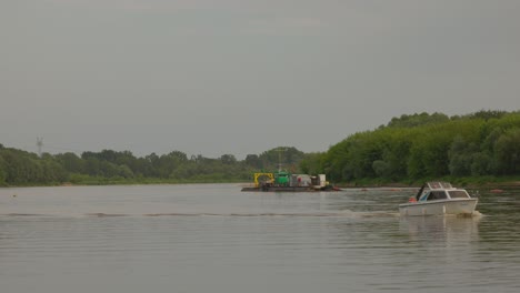 a small motorboat passing a large workboat on a calm river