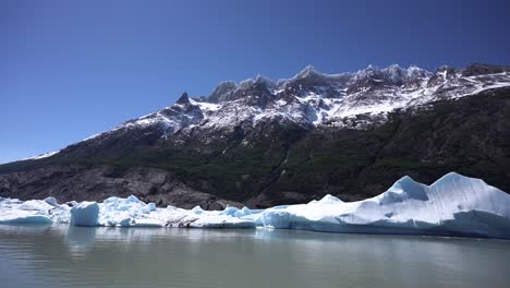 Glacier-lake-with-a-mountain-with-snow-on-peaks-in-the-background,-static-shot