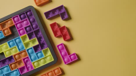 studio overhead shot of coloured interlocking shape puzzles on yellow background for child diagnosed with asd