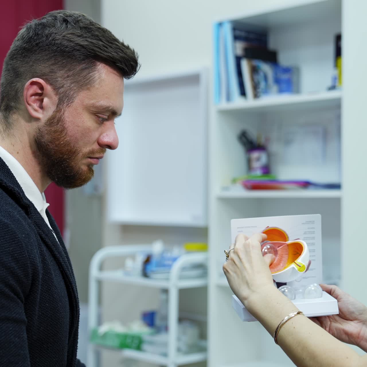 Optical specialist and young man in medical center. Doctor optometrist explaining to a male patient the eye care on an eye layout