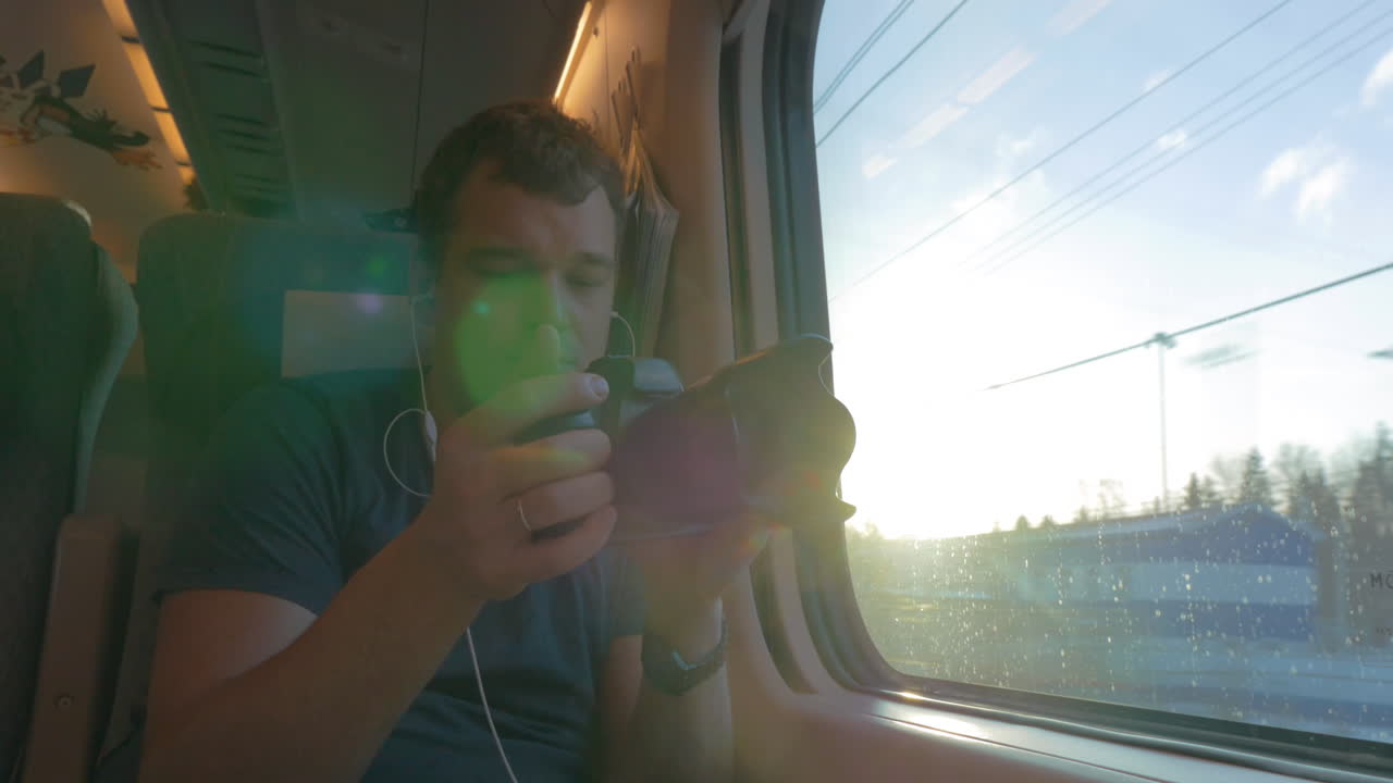 hombre viajero filmando video a través de la ventana del tren