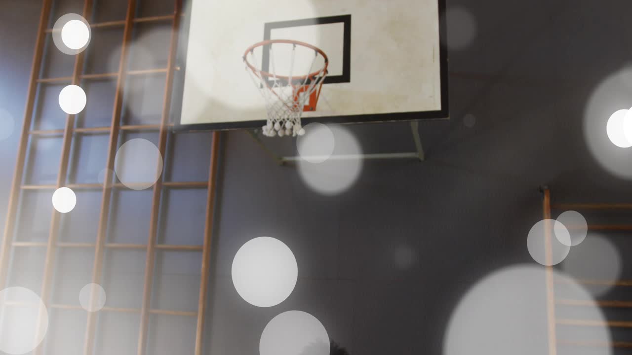 Giocatore con la maglia rossa che palleggia a basket in palestra, in penetrazione verso il canestro sotto la pressione del difensore.