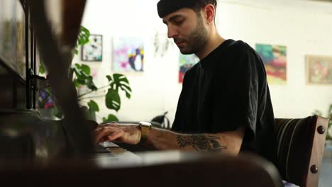 Slow-motion-of-young-man-sitting-in-front-of-old-wooden-piano-and-playing