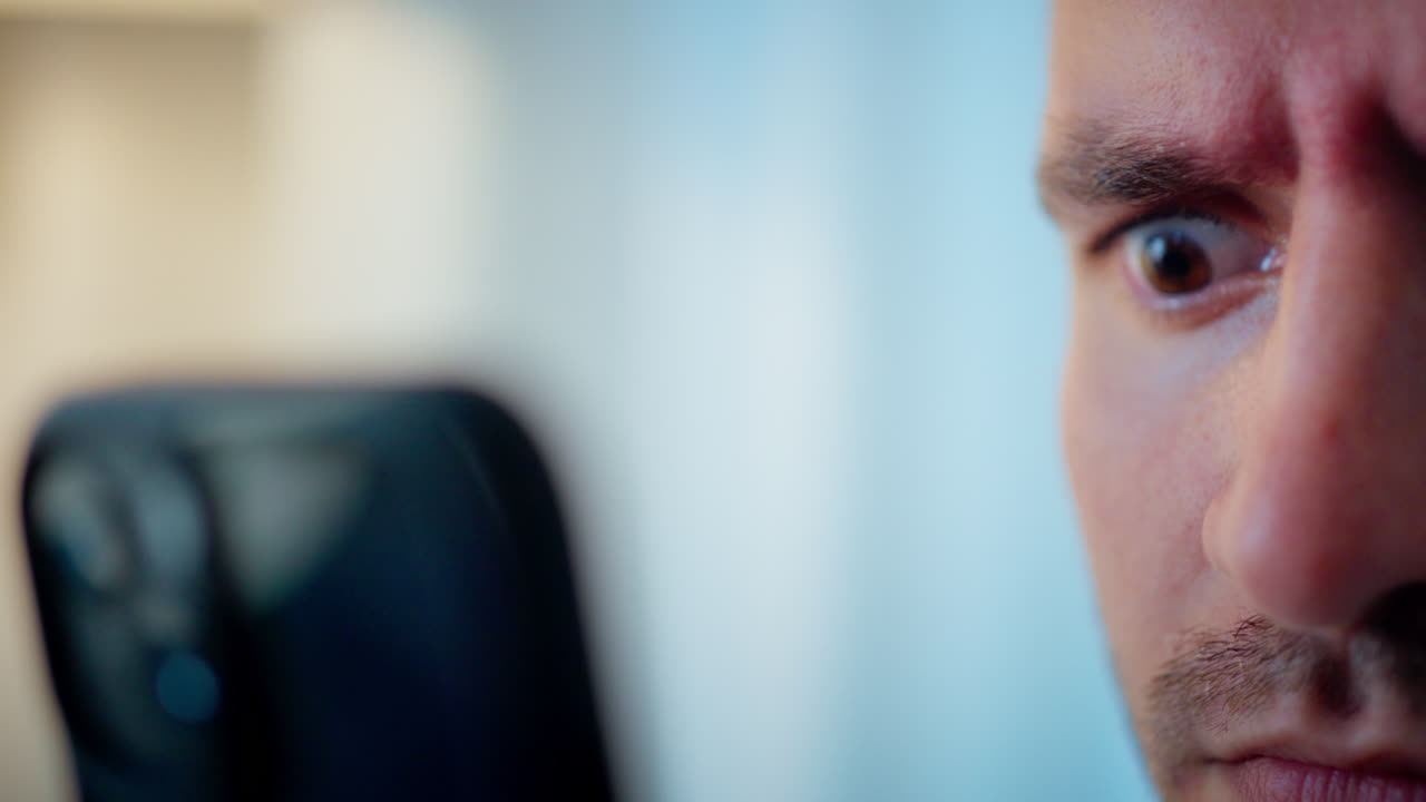 Close-up of a man looking at his phone with anxiety