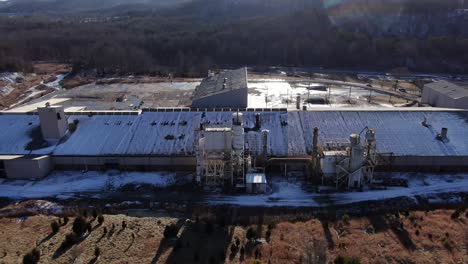 aerial drone footage panning down, flying towards an abandoned brick factory in the middle of winter