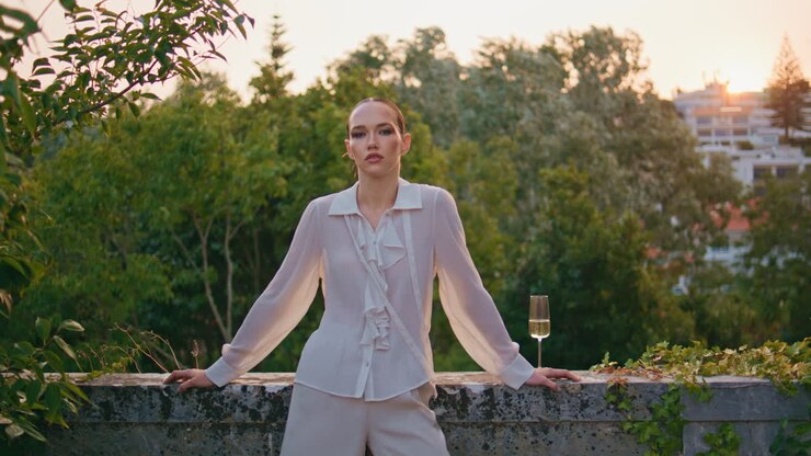 уверенная женщина позирует на балконе старого здания. прекрасная девушка с бокалом вина.