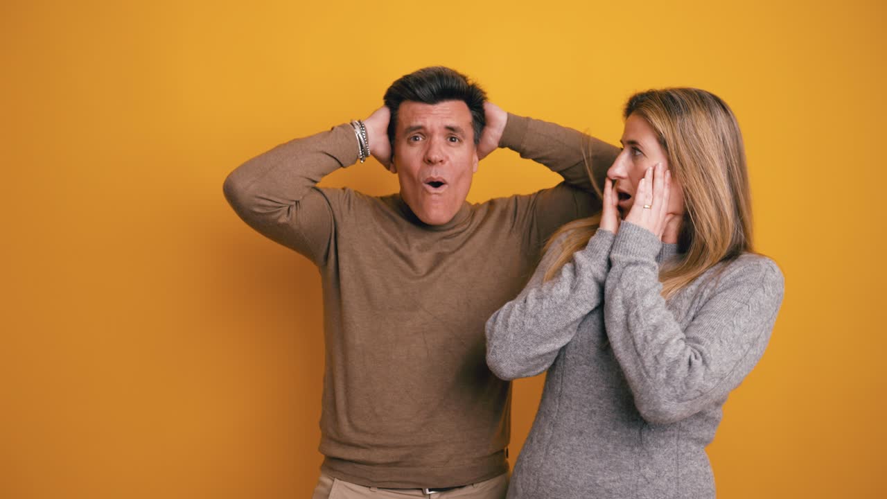 Uomo e donna sorpresi che reagiscono con stupore su sfondo giallo