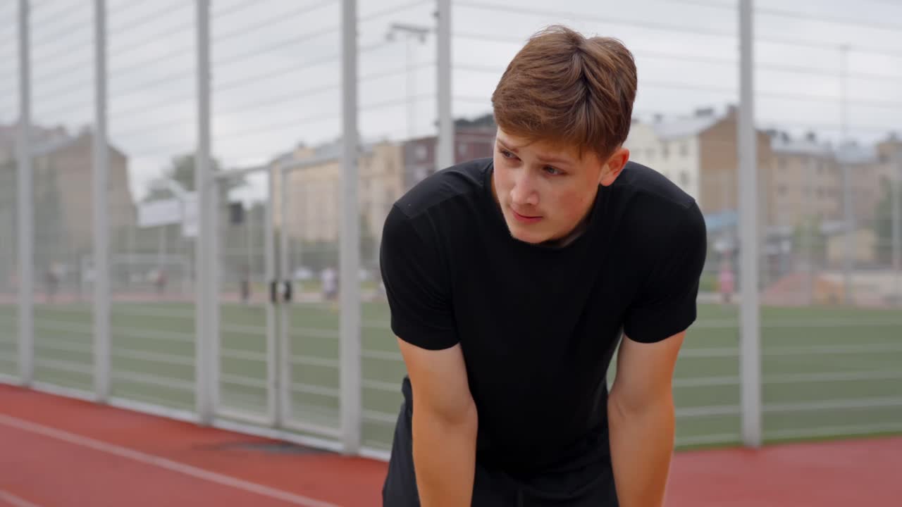 Orbit shot of man bent forward tired after training session catching breath in park