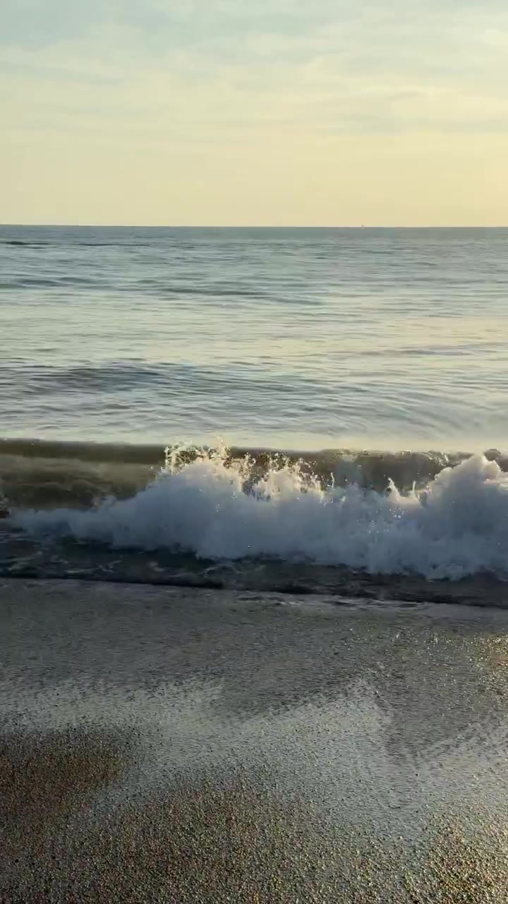 Onde oceaniche tranquille che si infrangono a riva su una spiaggia sabbiosa.