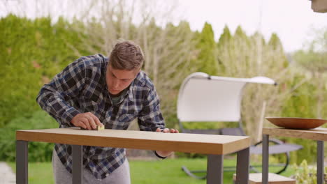 man sanding a wooden outdoor table