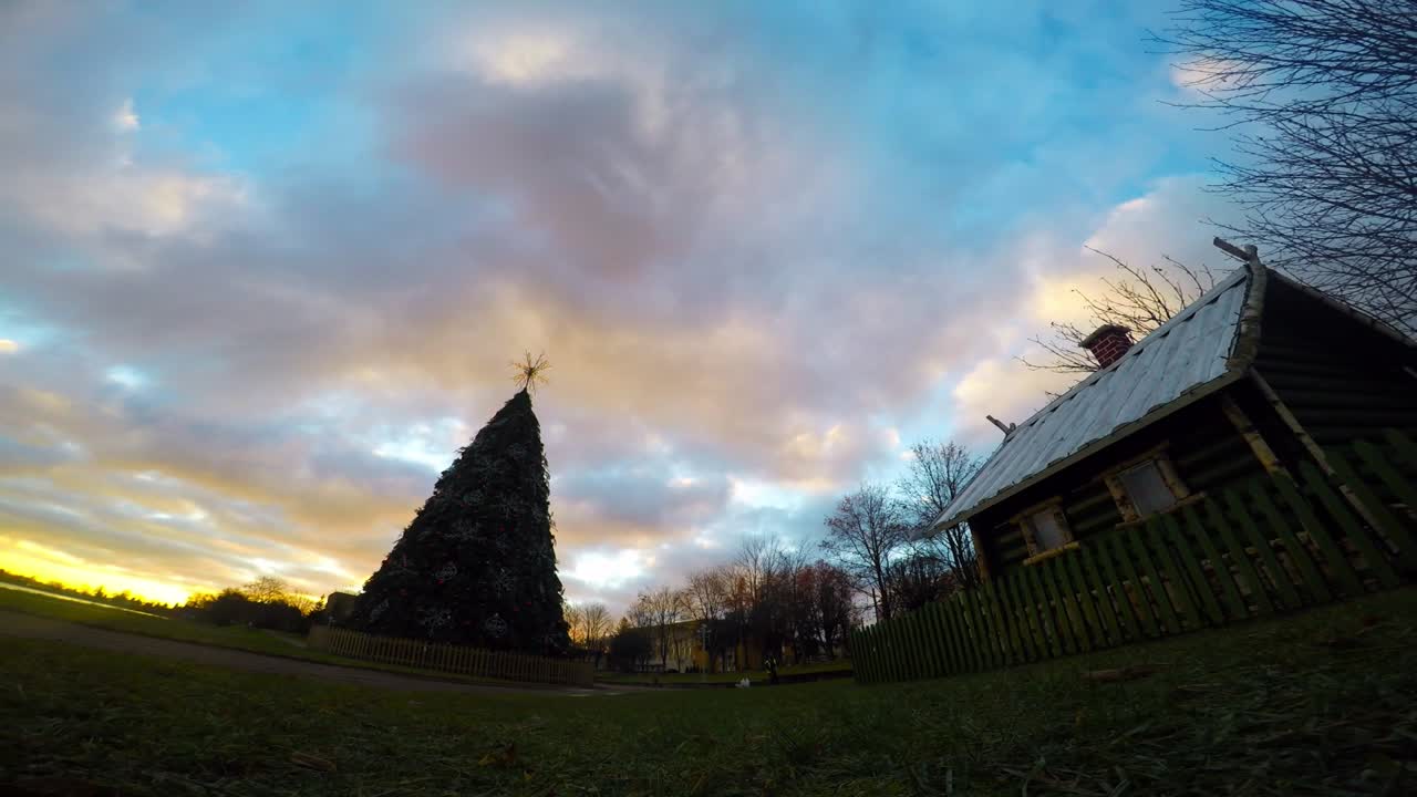 nubes dramáticas sobre el árbol de navidad y la pequeña casa de madera