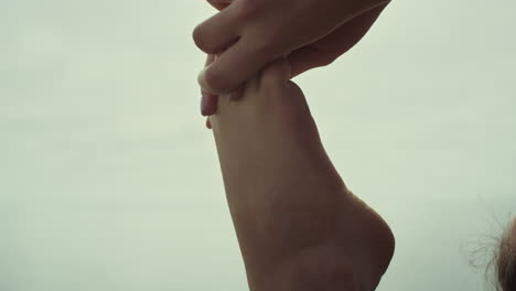 closeup girl bare feet stretching beach. young sportswoman doing yoga exercise.