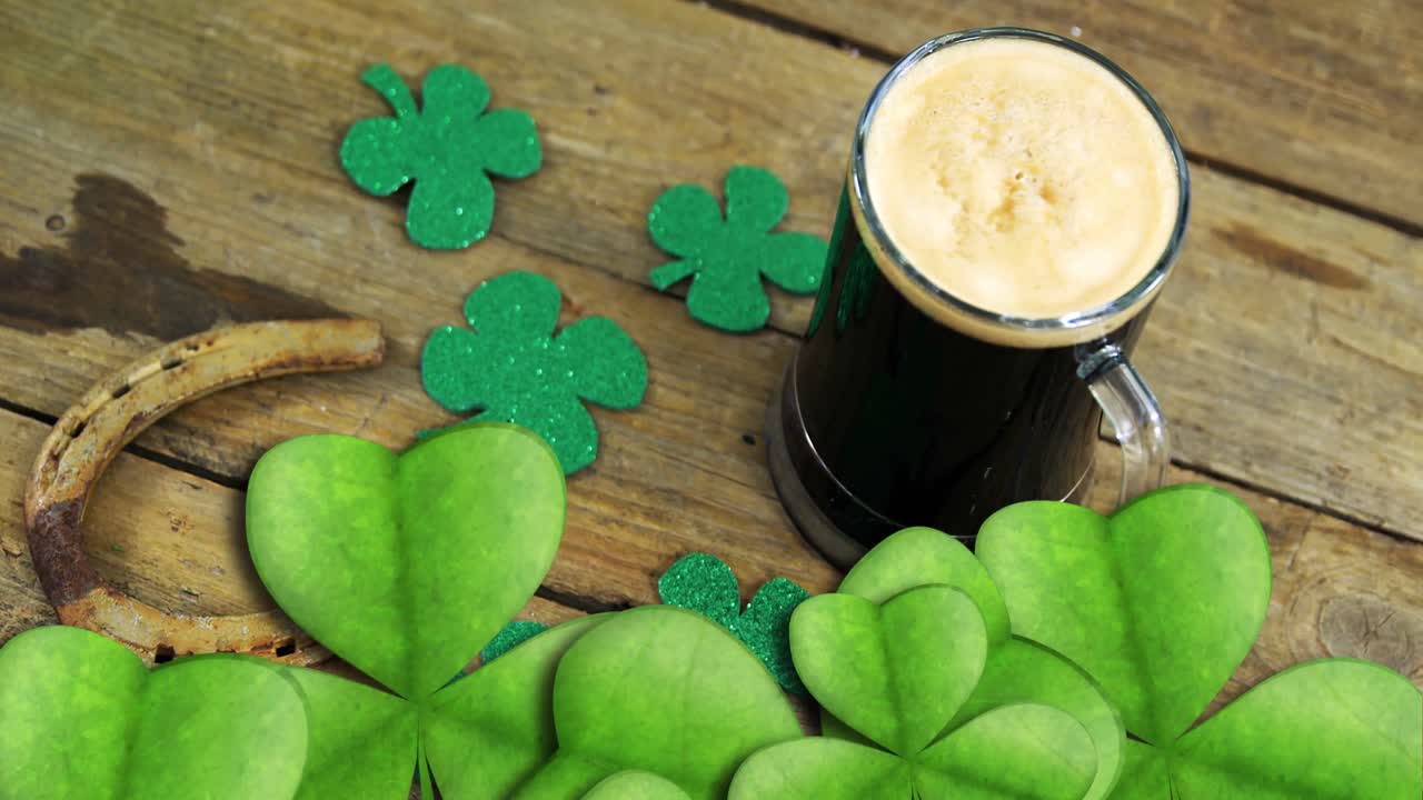 Animation of st patrick's day shamrock and glass of beer on wooden background